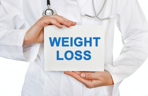 man in white coat holding weight loss sign
